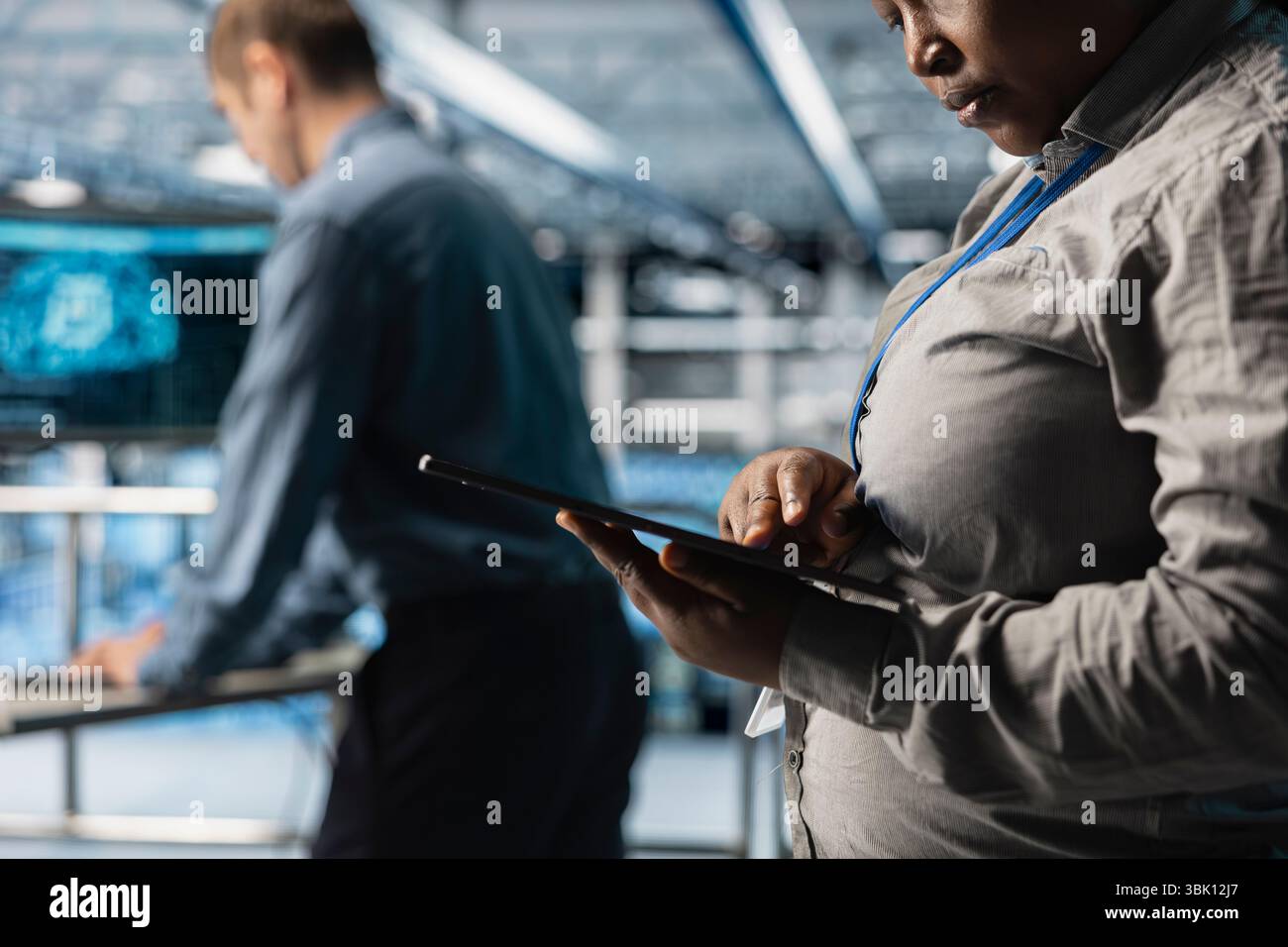 Close up of server room coworkers reviewing network configurations using software on tablet. Teamworking data center technicians tracking resource utilization trends using device Stock Photo