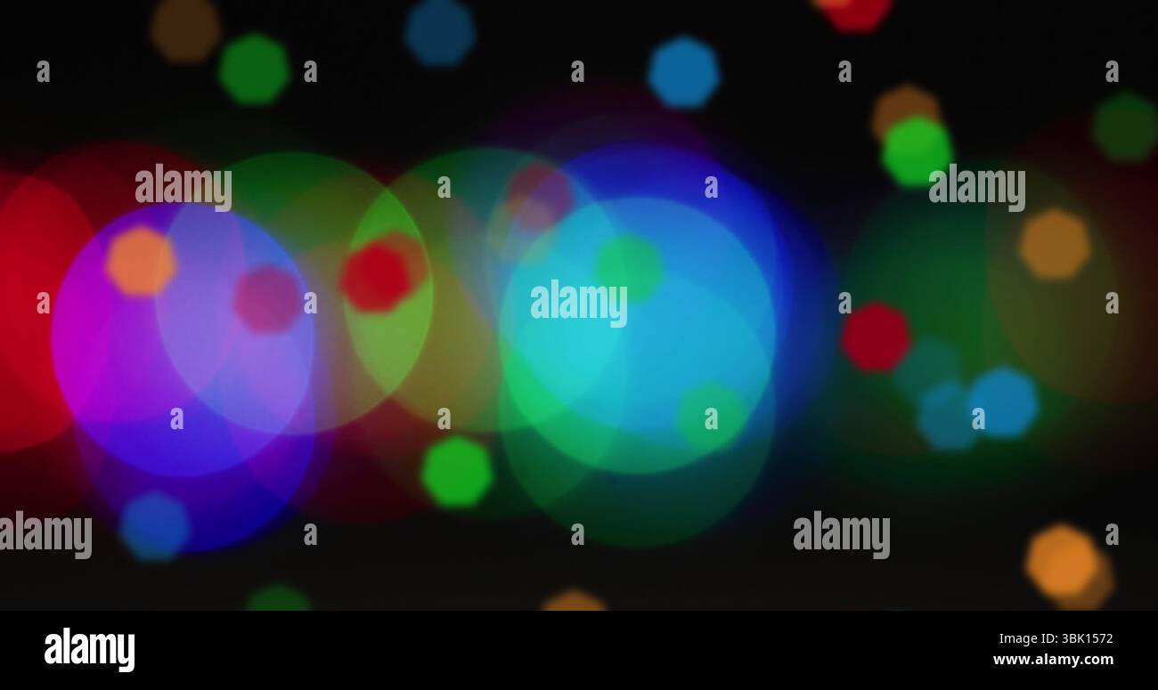 Showing overlapping colored light circles dancing across black background, with abstract bokeh Stock Photo