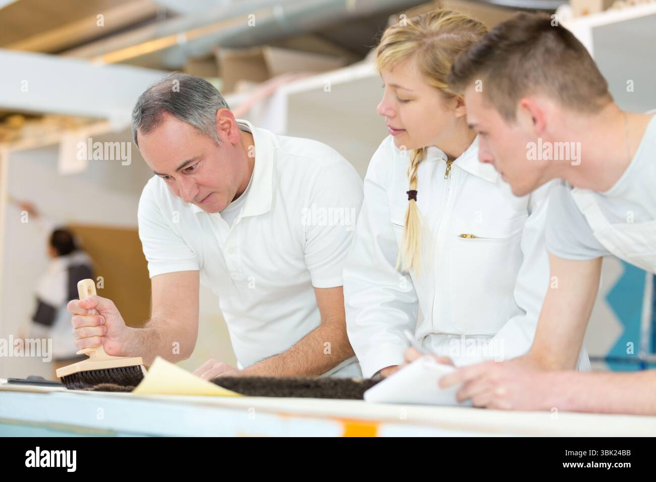instructor showing apprentices using a brush Stock Photo