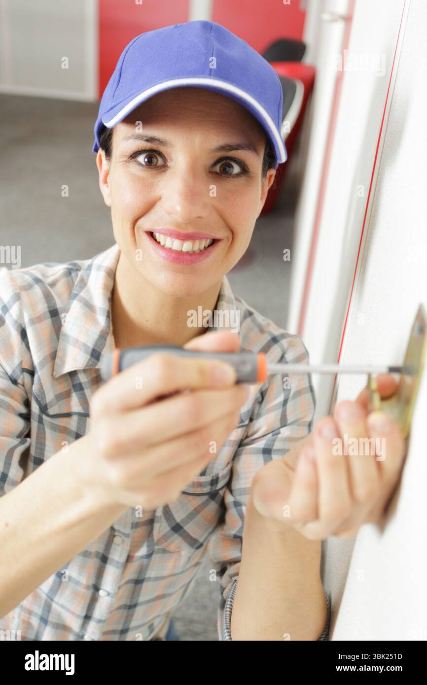 happy woman using screw driver during socket installation Stock Photo