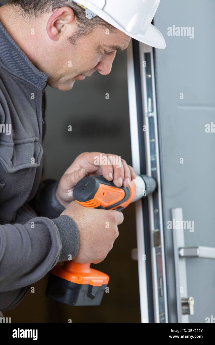 builder wearing protective workwear and holding electric drill Stock Photo