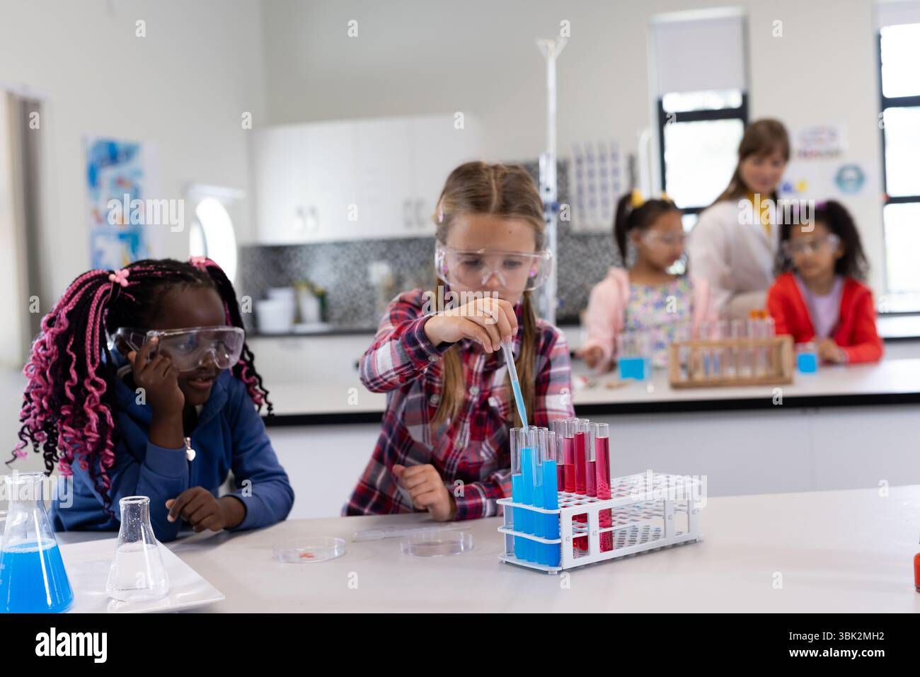 Diverse school children conducting science experiments with test tubes in classroom Stock Photo