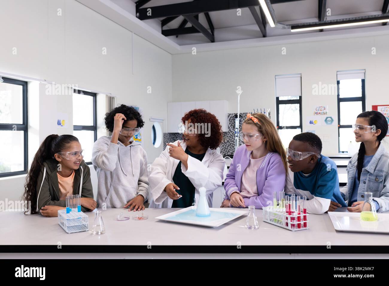 Conducting science experiment, diverse students with female teacher in school lab Stock Photo