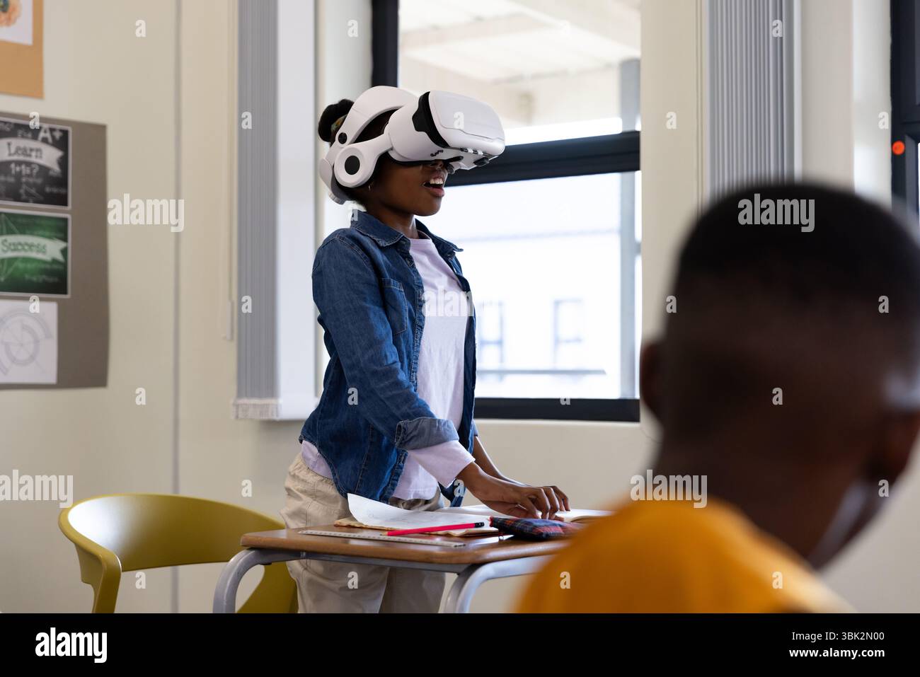Girl using VR headset in classroom, exploring virtual reality technology, at school Stock Photo
