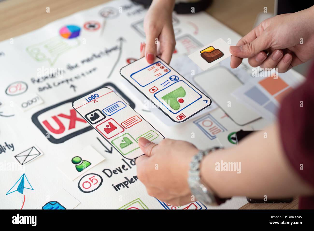 Collaborative UX Design. Team members discussing user interface elements on design board. Stock Photo