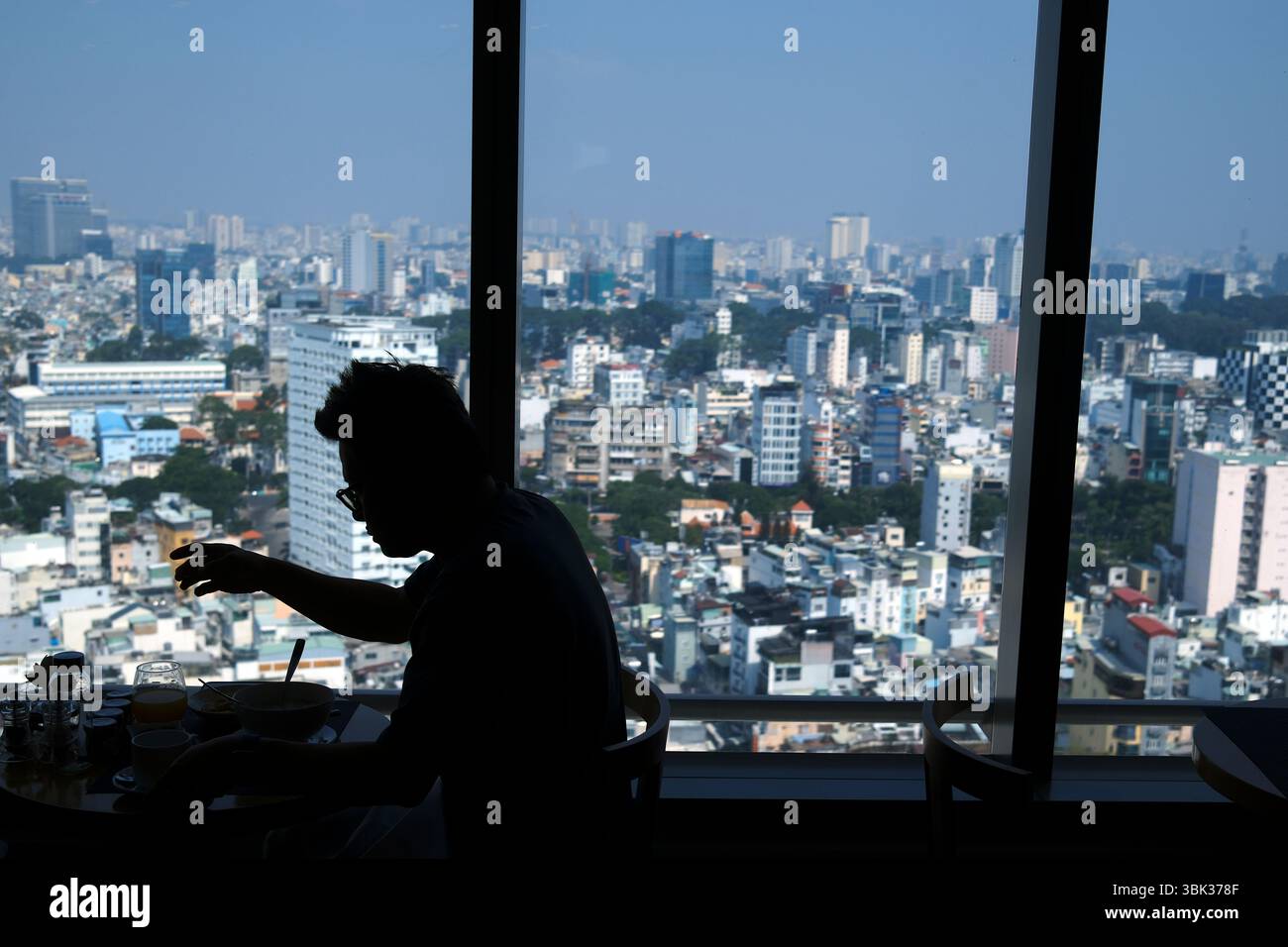 Silhouette of a man against the light with the megalopolis of Saigon in the background. Ho Chi Minh city. Vietnam. Stock Photo