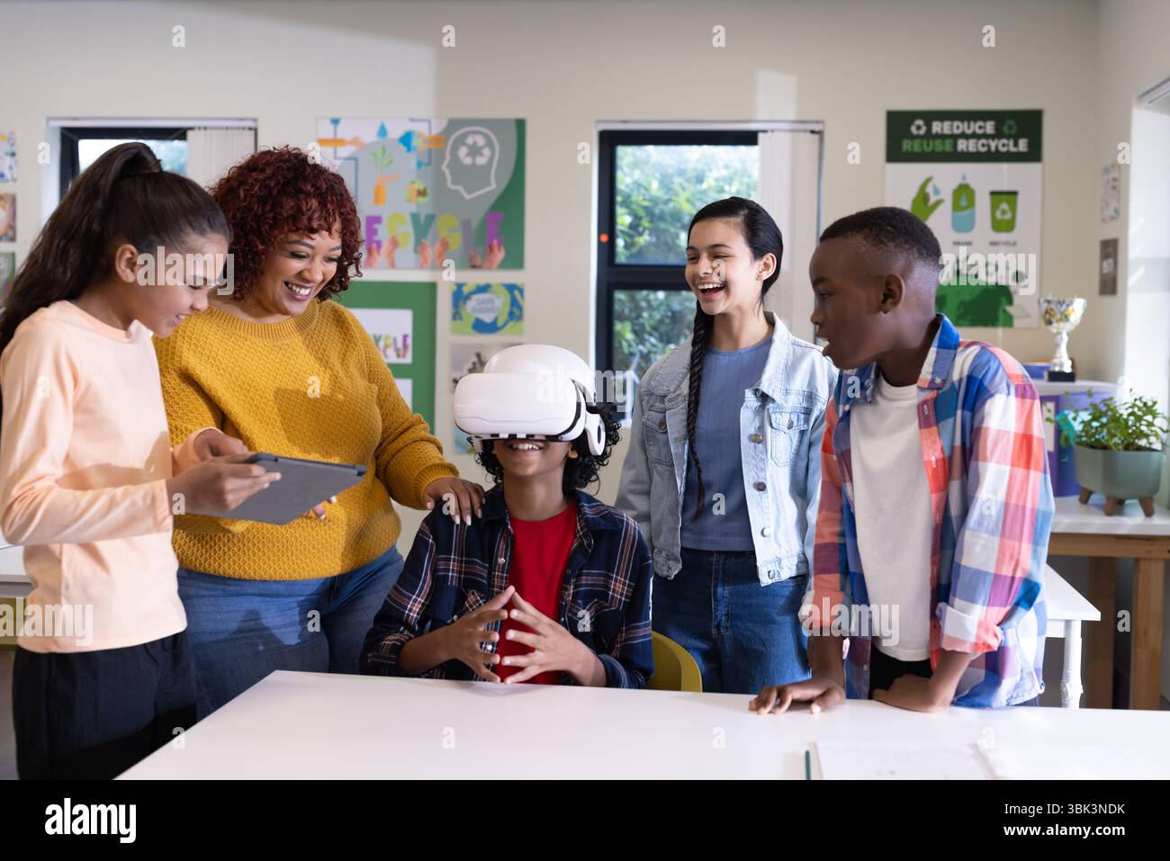 In school, diverse students using virtual reality, smiling and interacting in classroom Stock Photo