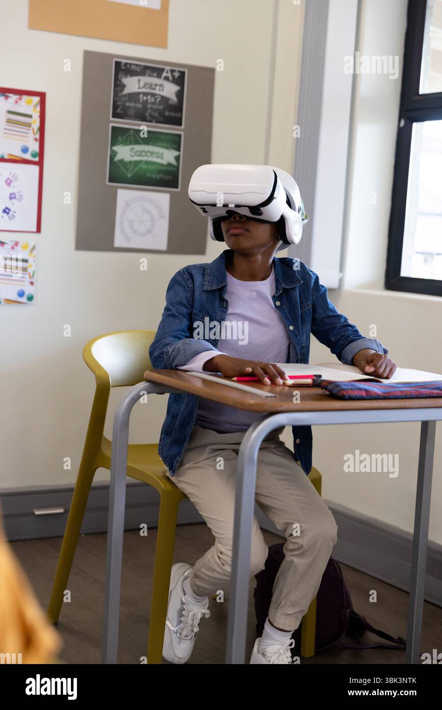 Girl using VR headset in classroom, exploring virtual learning experience, at school Stock Photo