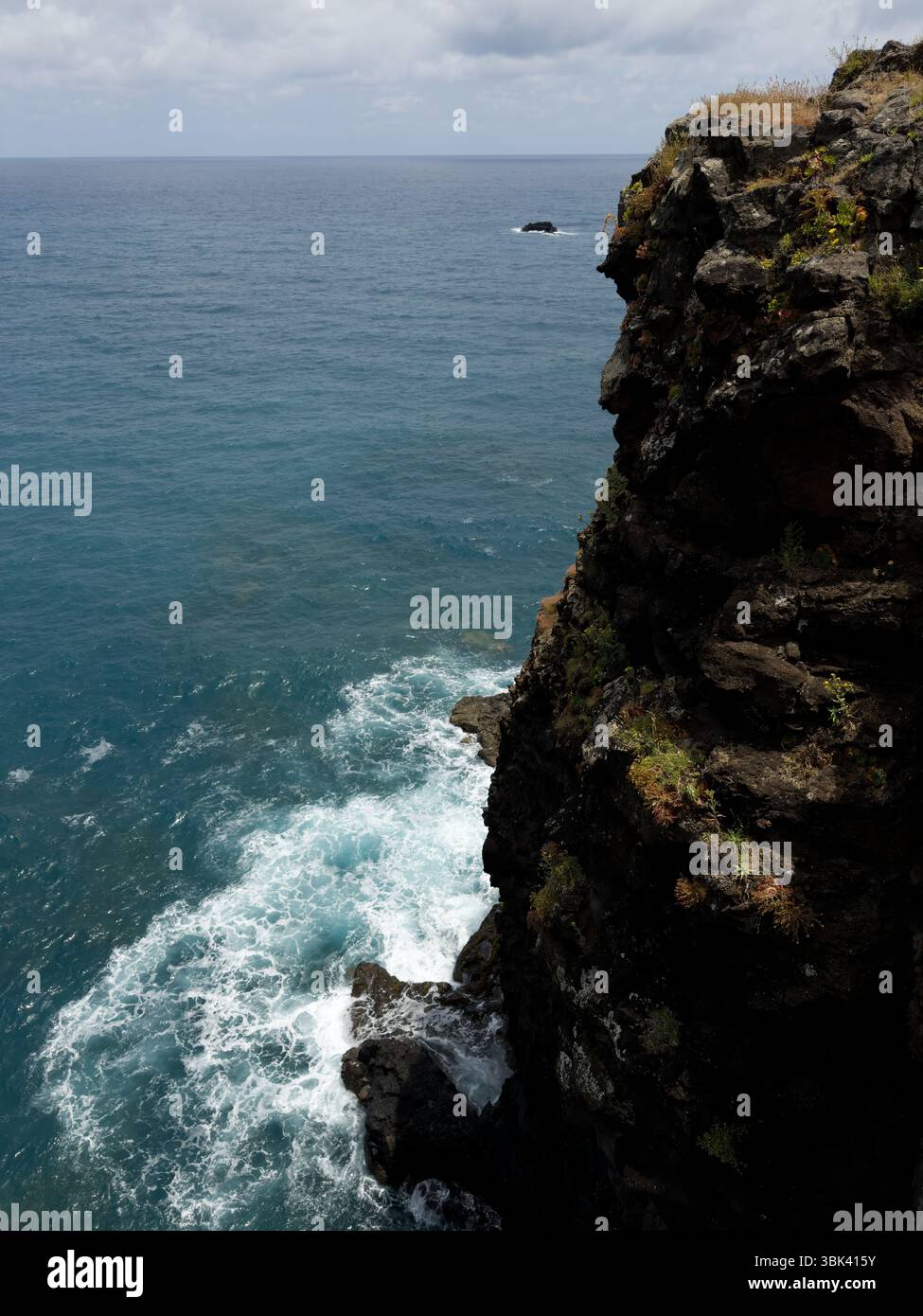 Vertical shoot. Ocean waves crashing against rocky coastline on the coast of Madeira, Portugal. Seascape with white surf sea spray and rugged stones. - Smartphone Captured Stock Image