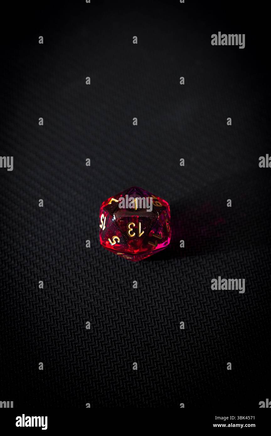 A dramatic minimalist photo of a single translucent red 20-sided die ...