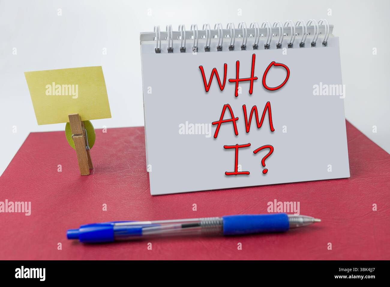 Who Am I written on a notebook on a red background Stock Photo