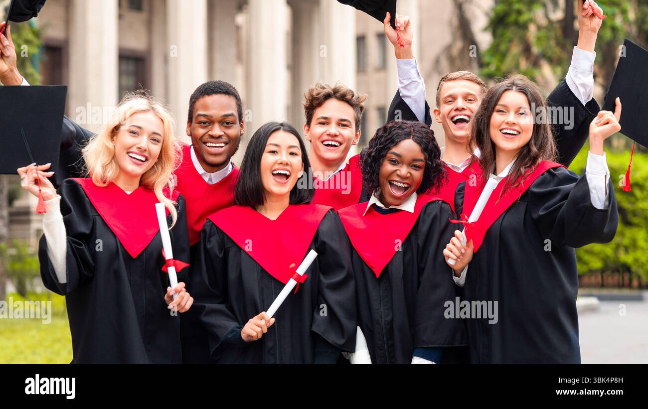 Joyful multiethnic students with diplomas celebrating graduation Stock Photo