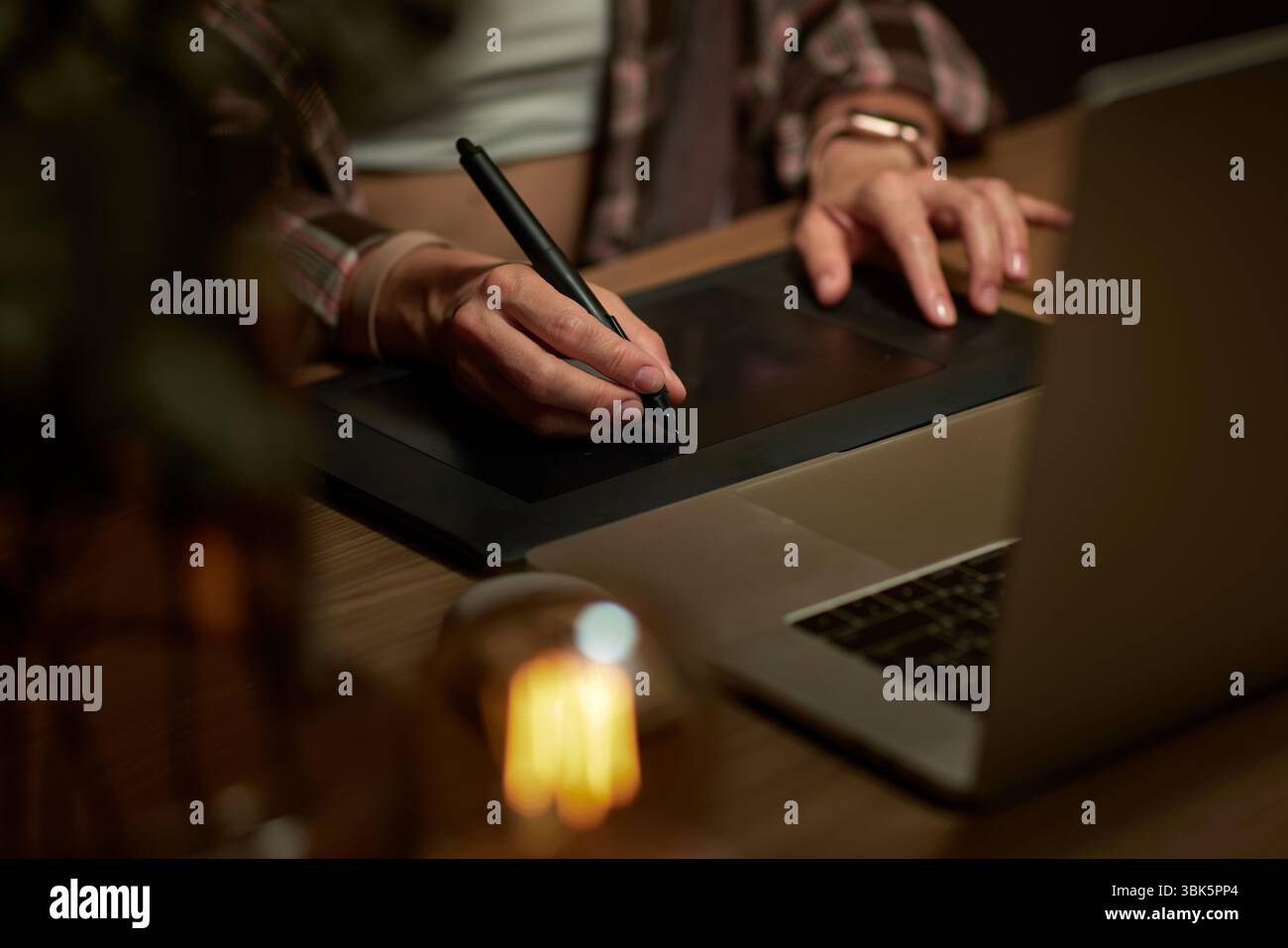 female hands with graphic tablet retouching photo on laptop computer at night Stock Photo