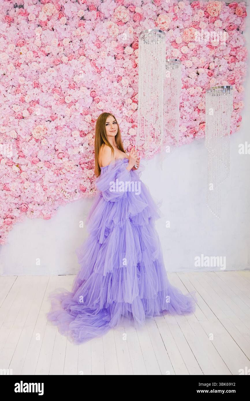 A young Caucasian woman with long brown hair wears a flowing purple ...