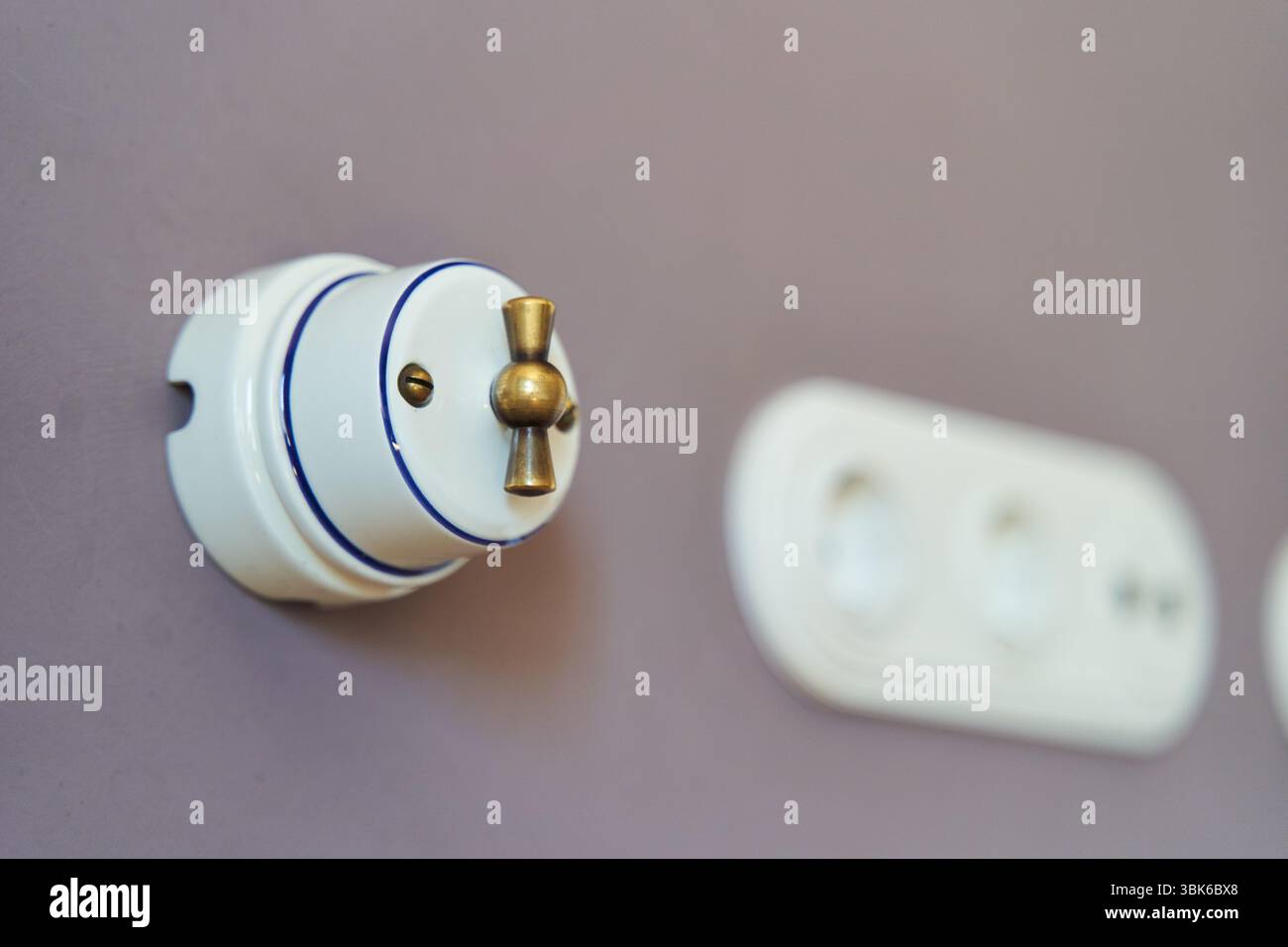 Retro style light switch and socket on dark pink wall Stock Photo