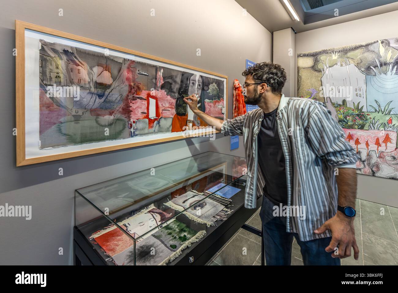 An employee of the Cité internationale de la tapisserie explains the special features of the tapestry "Hommage à George Sand" by Françoise Petrovitch. The materials and colours used in the tapestry were selected and implemented in close collaboration with experts from the Cité internationale de la tapisserie Aubusson. Rue des Arts, Aubusson, Nouvelle-Aquitaine, France Stock Photo