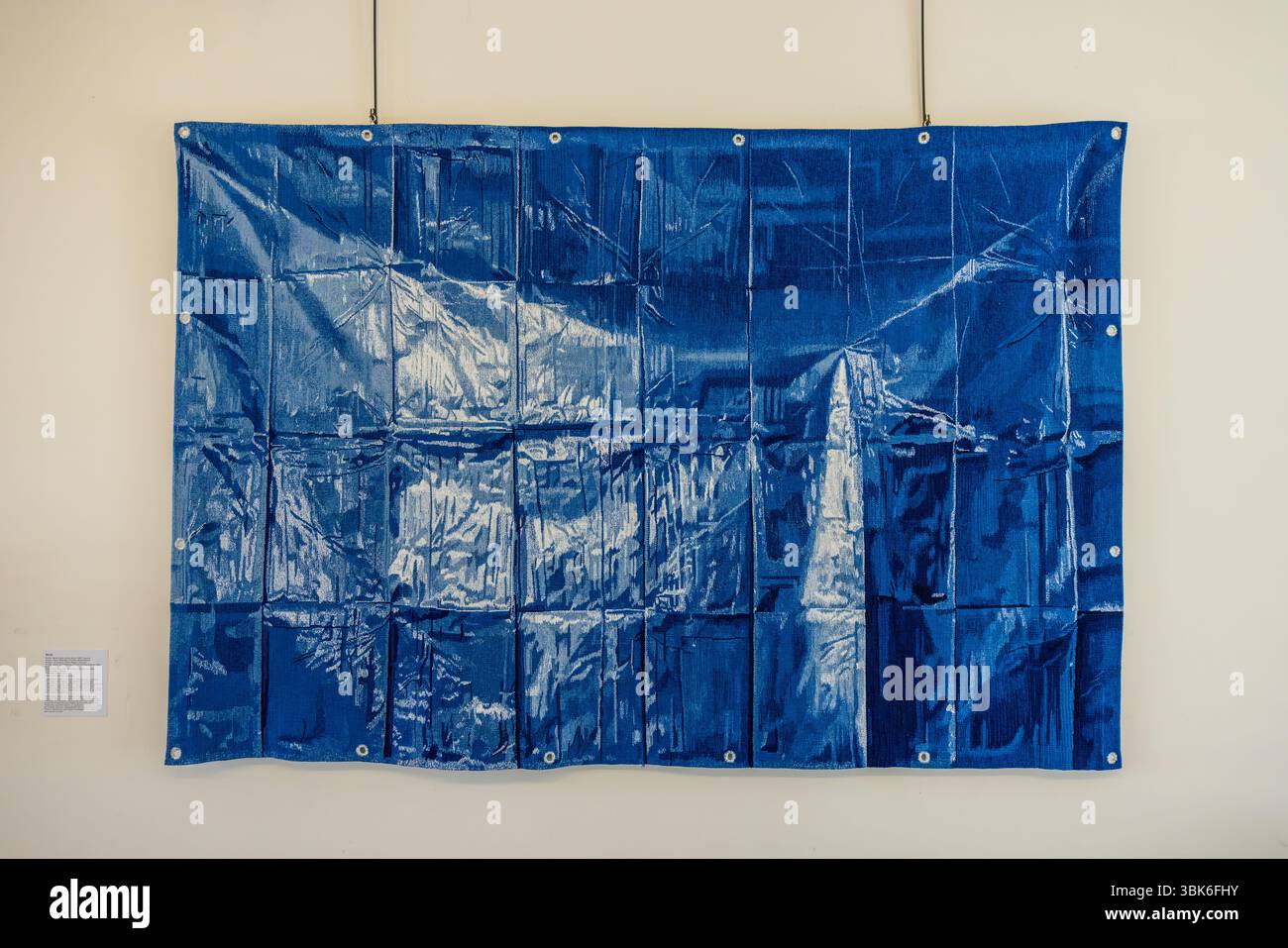 The art of optical illusion. This is not a plastic sheet but a tapestry. "Blue" by Marie Sirgue. On closer inspection, the shiny plastic sheet turns into a perfectly woven, flat silk carpet measuring 3 metres by 2 metres. Rue Williams Dumazet, Aubusson, Nouvelle-Aquitaine, France Stock Photo