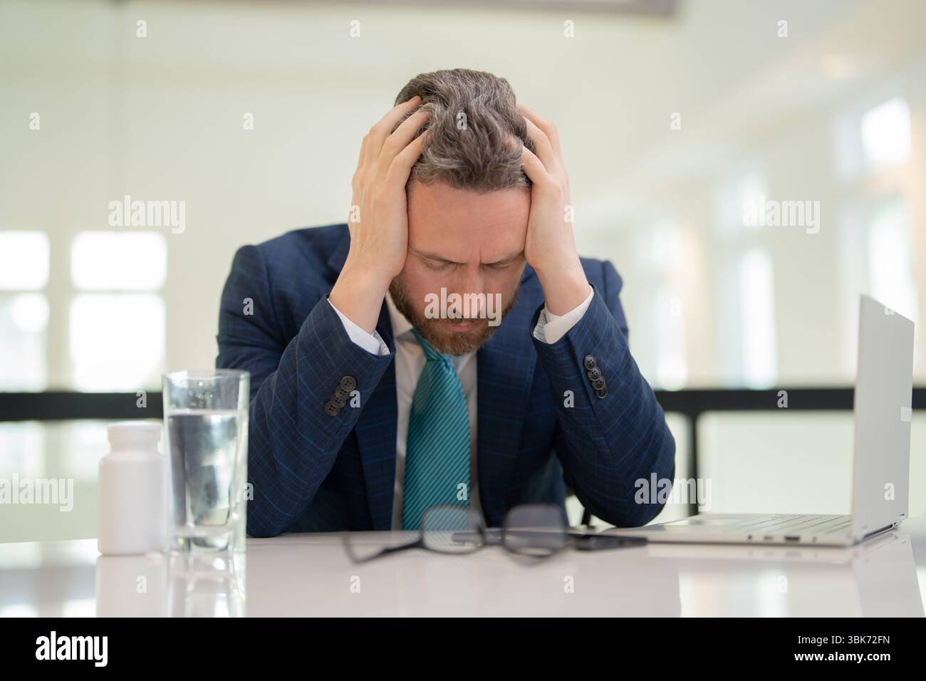 Tired man having a terrible headache. Exhausted man feeling unhealthy, upset about headache illness. Stressed middle-aged man having headache Stock Photo