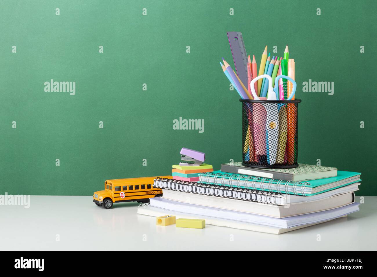 Colorful School Supplies Arranged on Desk With Green Background, chalkboard, back to school concept Stock Photo