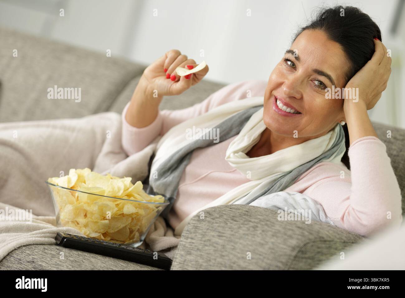a woman is eating chips Stock Photo - Alamy