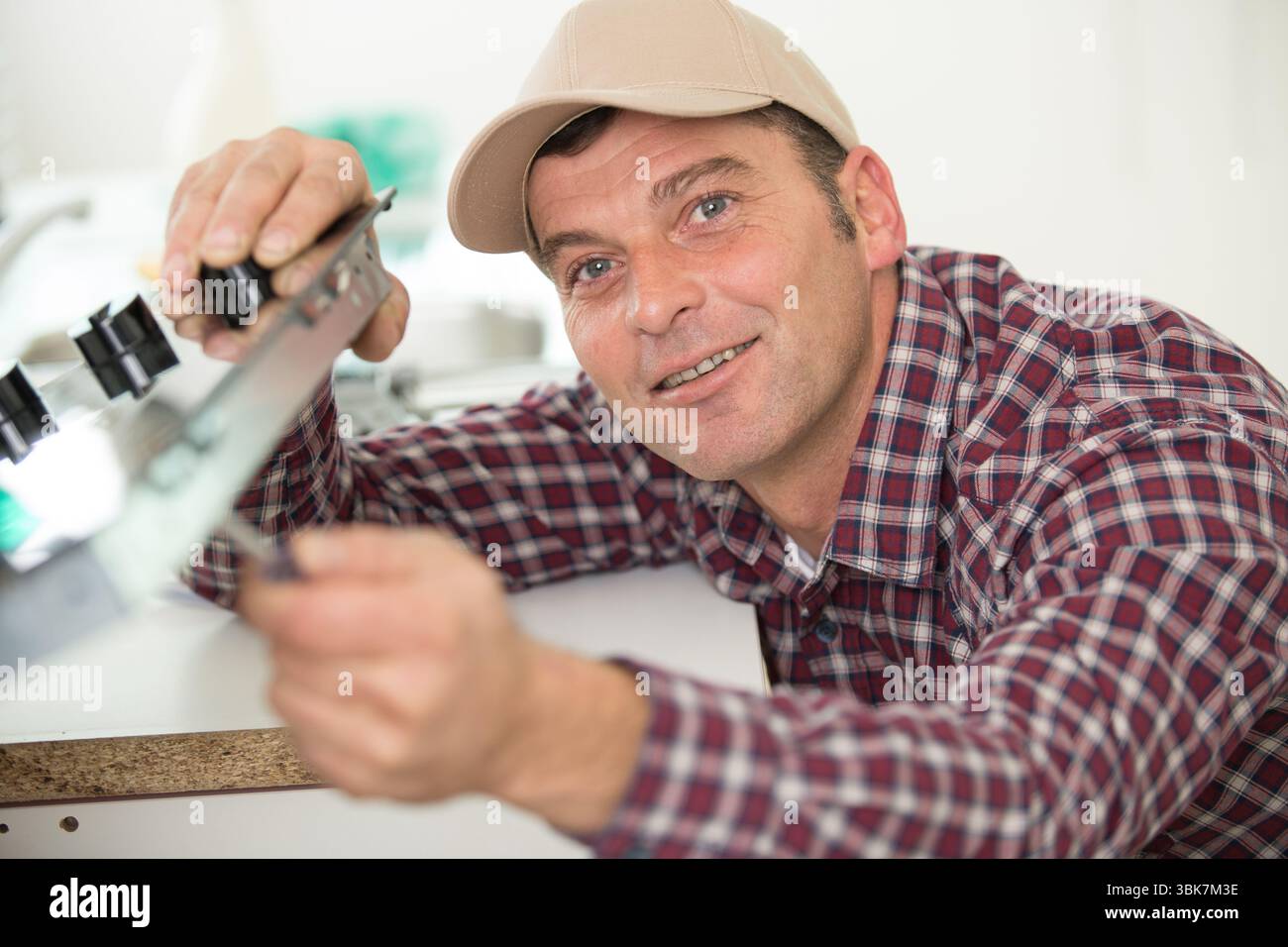 young contractor repairing oven in kitchen Stock Photo