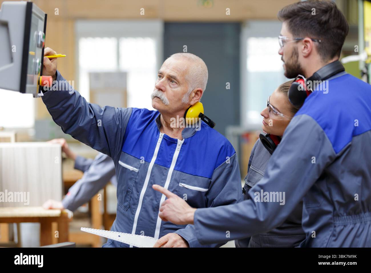 senior engineer and apprentices checking computer in a factory Stock Photo