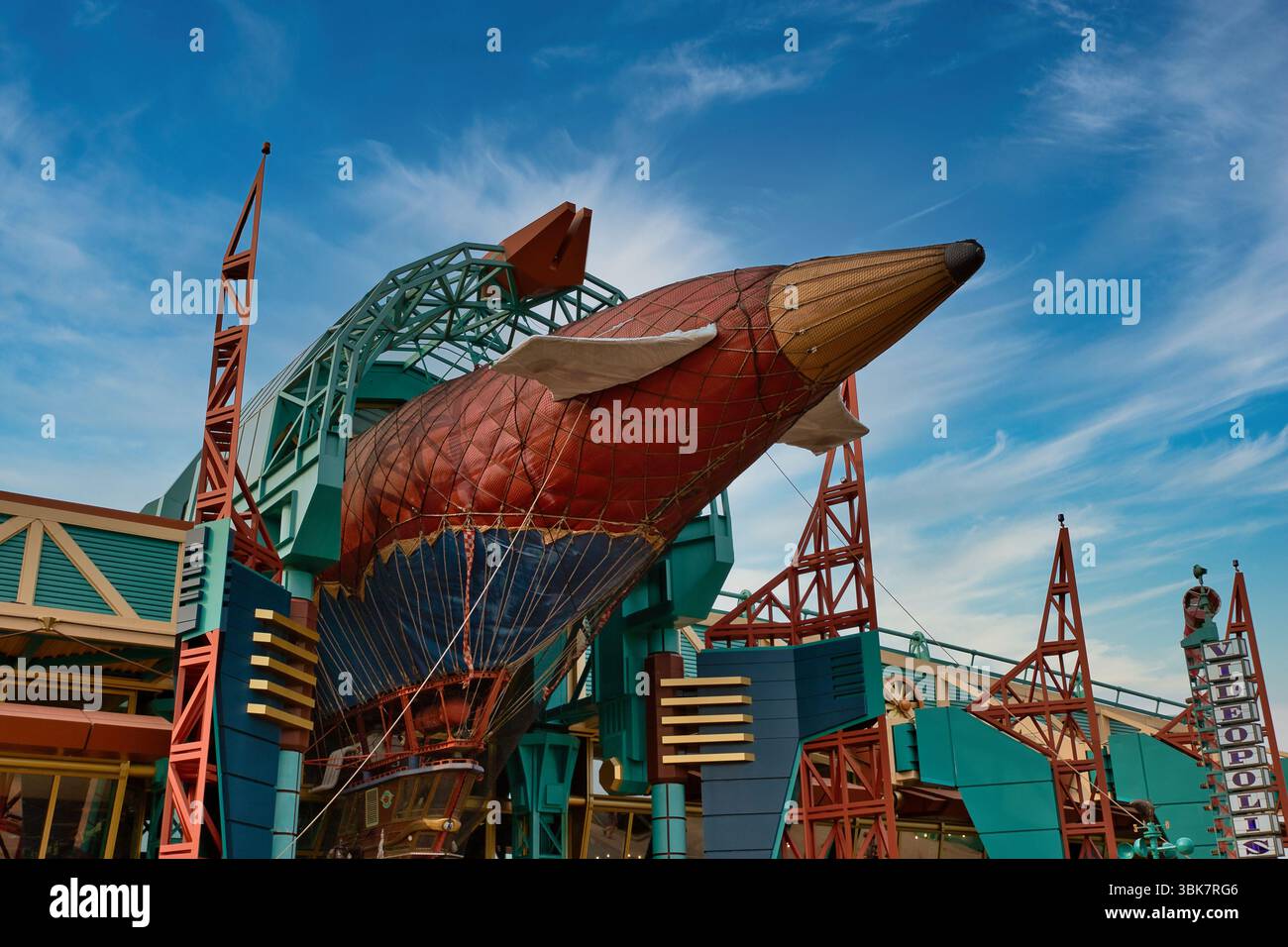 A large airship structure, primarily red, blue, and gold, sits amidst ...