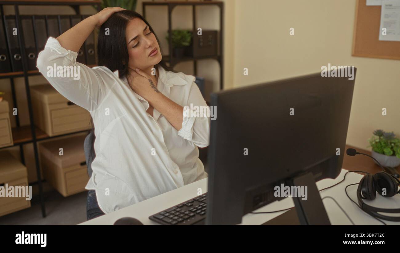 Woman with curvy figure stretches neck at office desk indoors ...