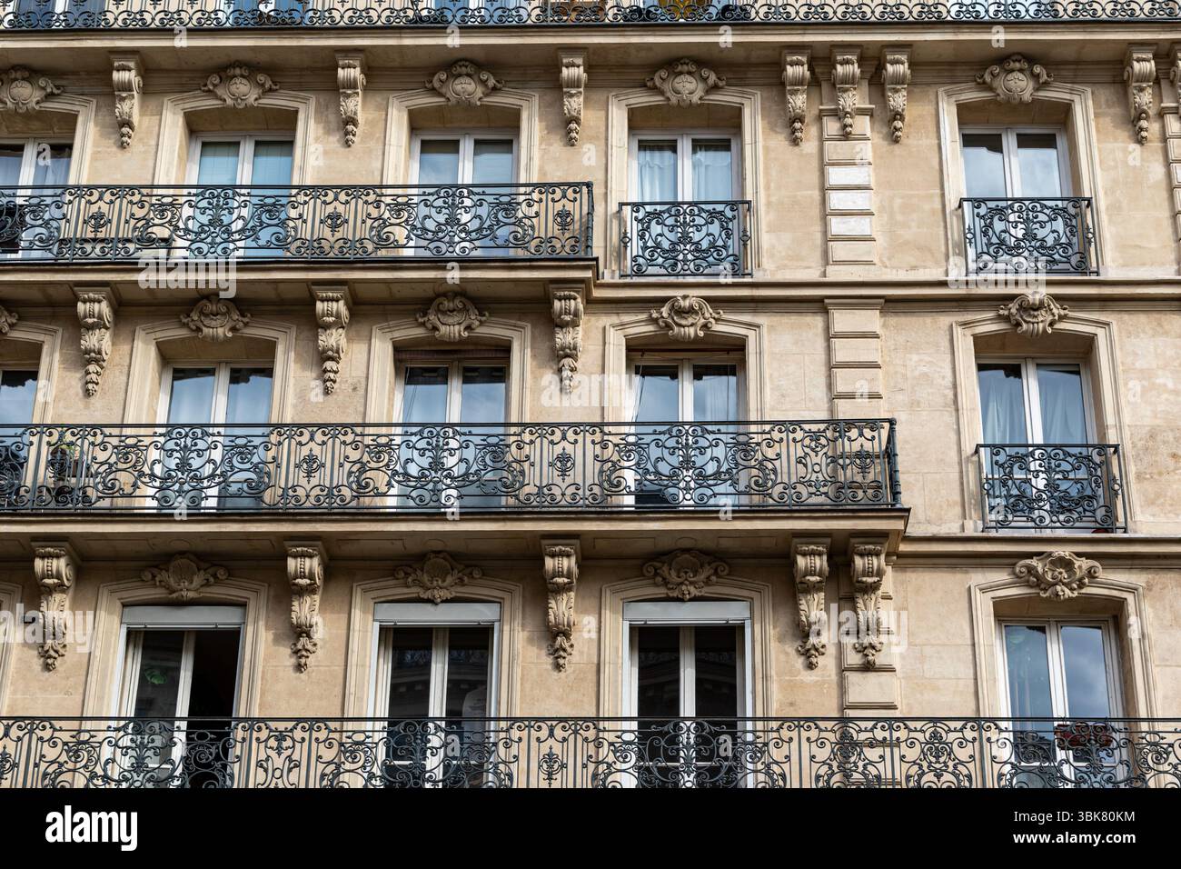 Facade of a multi-story building featuring windows with ornate iron ...