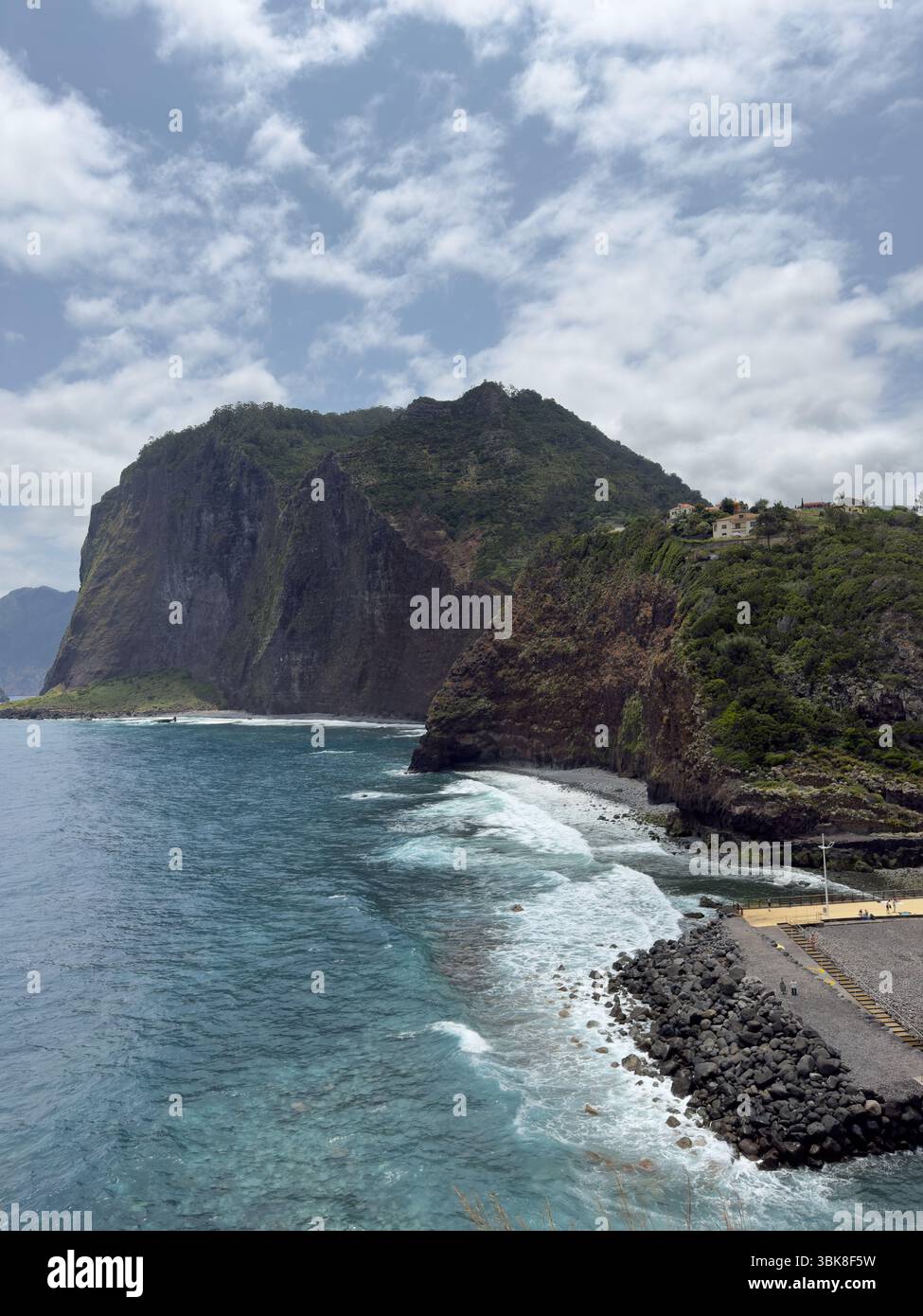Ocean waves crash against the rugged coastline of Madeira, Portugal, creating a breathtaking seascape with white surf, sea spray, and jagged stones. - Smartphone Captured Stock Image