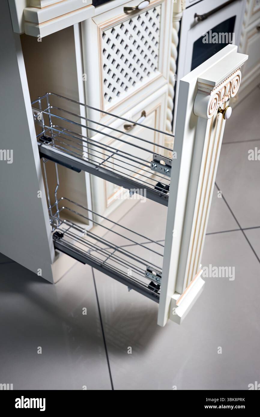 Pull out spice rack cabinet filler pantry. Interior of modern kitchen in classic style with golden elements in beige colors. Vertical drawer for spice Stock Photo