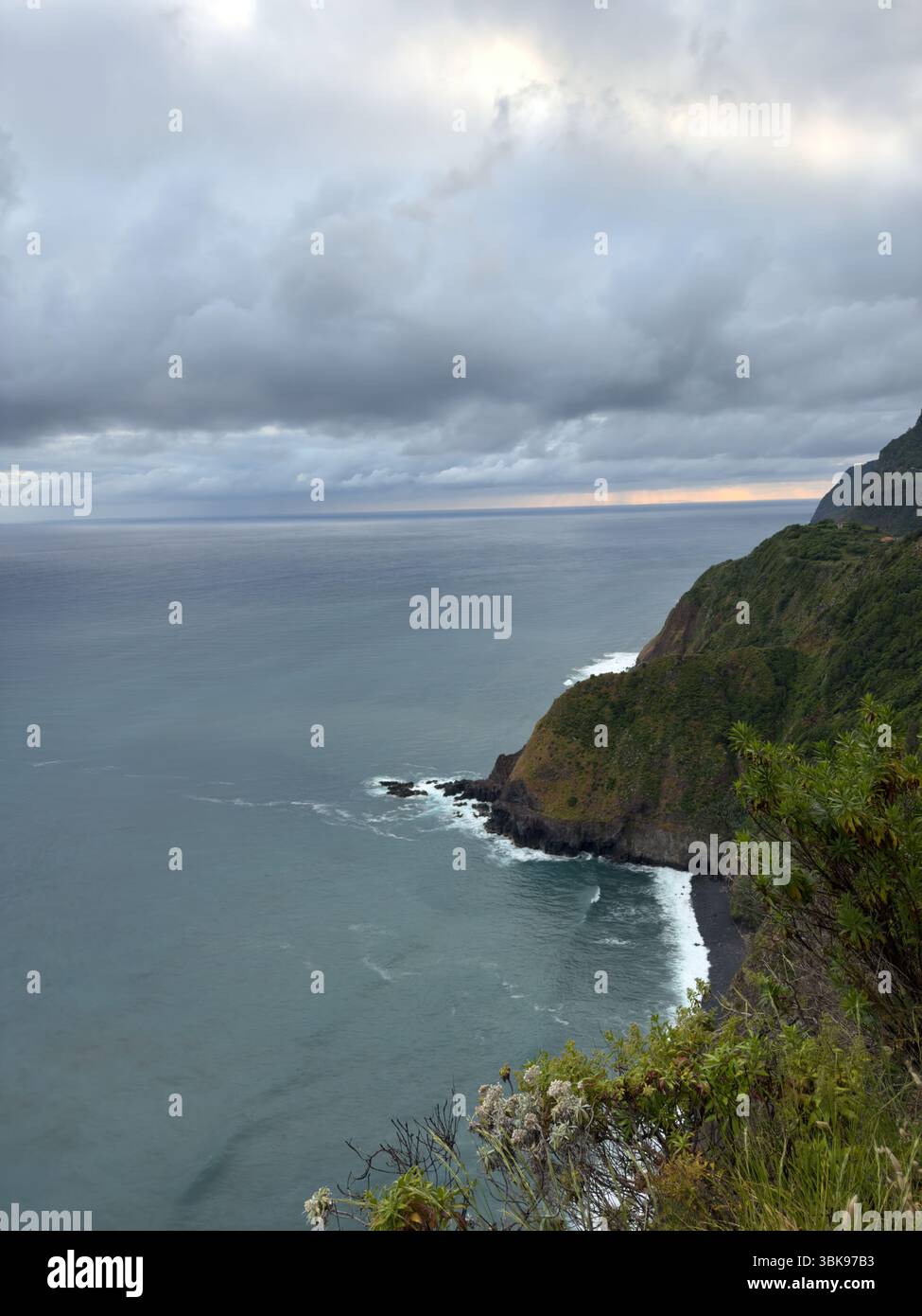 The rugged coastline of Madeira Island in Portugal and ocean waves. A picturesque green shore with impressive views of jagged rocks. Travel concept - Smartphone Captured Stock Image