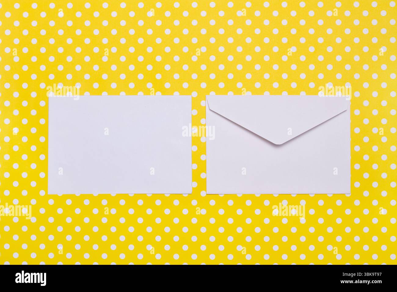 Two white envelopes on a yellow with white polka dots background with copy space Stock Photo