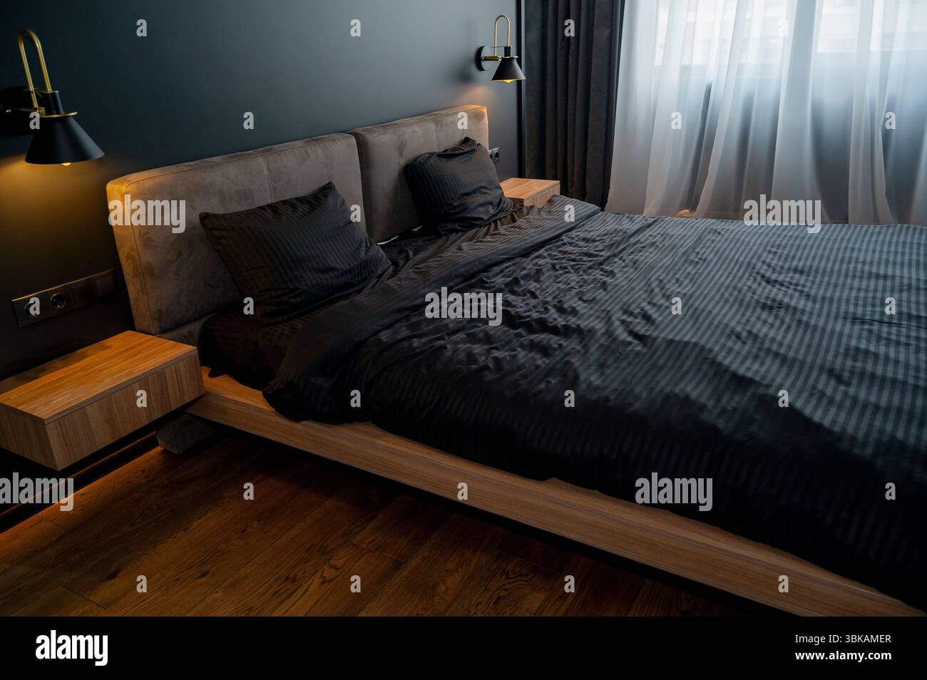 Modern bedroom with double bed in dark interior. On the bed there is black bed linen Stock Photo