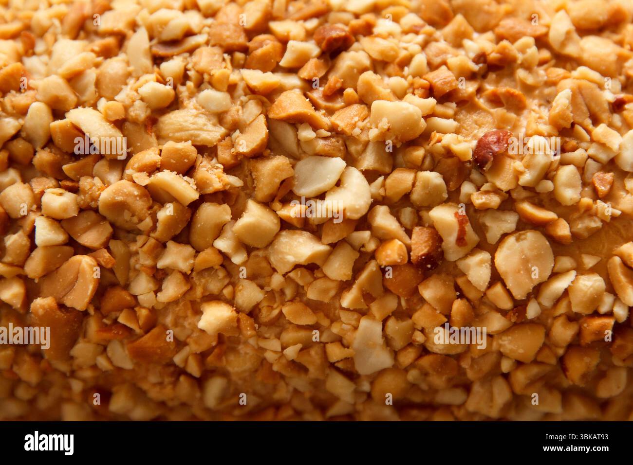 Crunchy crushed peanut texture covering a dessert surface, captured on a soft neutral background for culinary concept Stock Photo