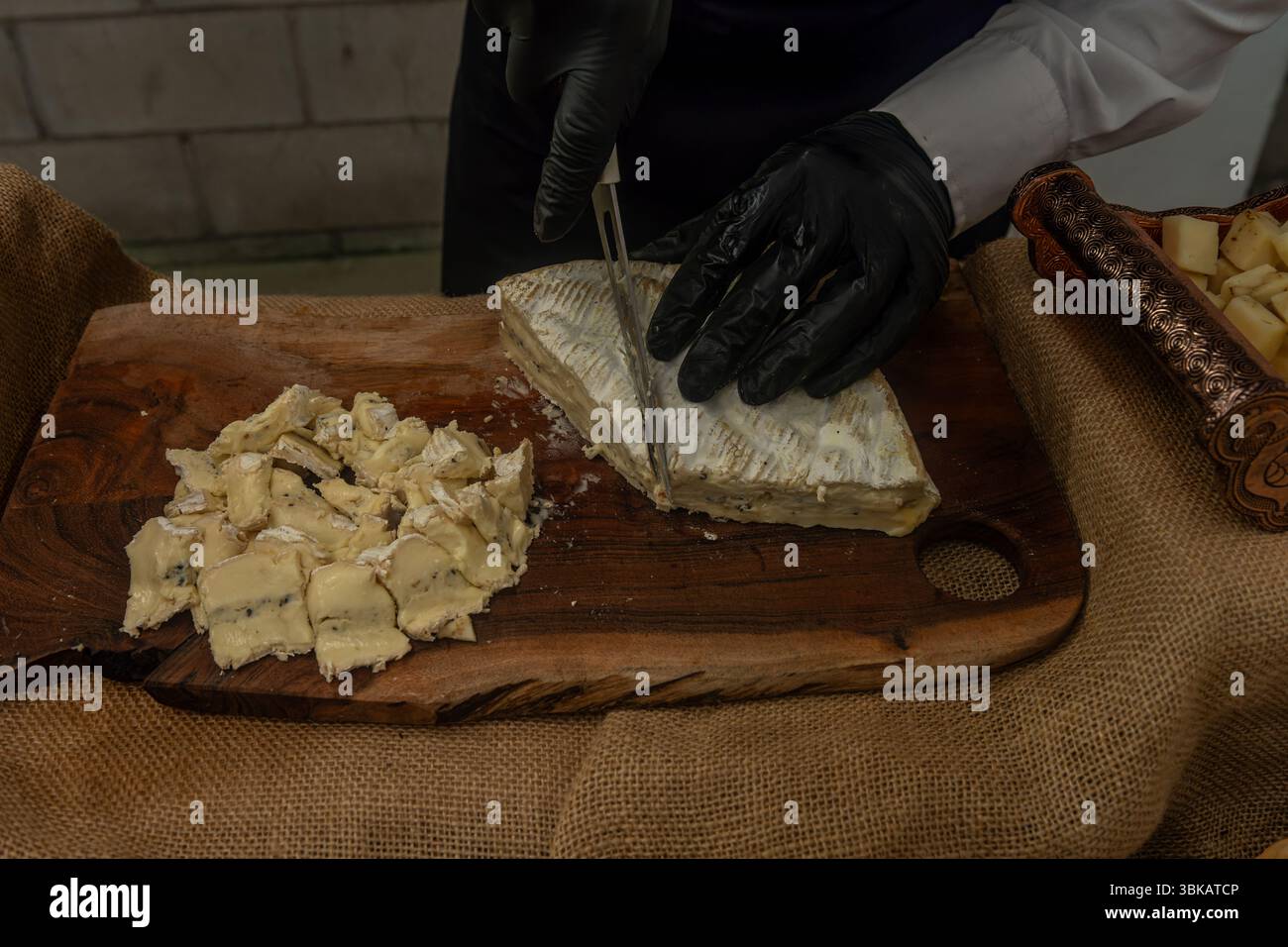 15 Ripened Cheese Soft ripened cheese being cut by gloved hands on a rustic wooden board ...