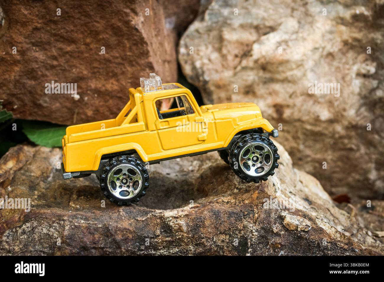 Miniature yellow 4x4 truck on rough rocky terrain, positioned dramatically at the edge of a cliff. Playful and creative small world adventure concept. Stock Photo