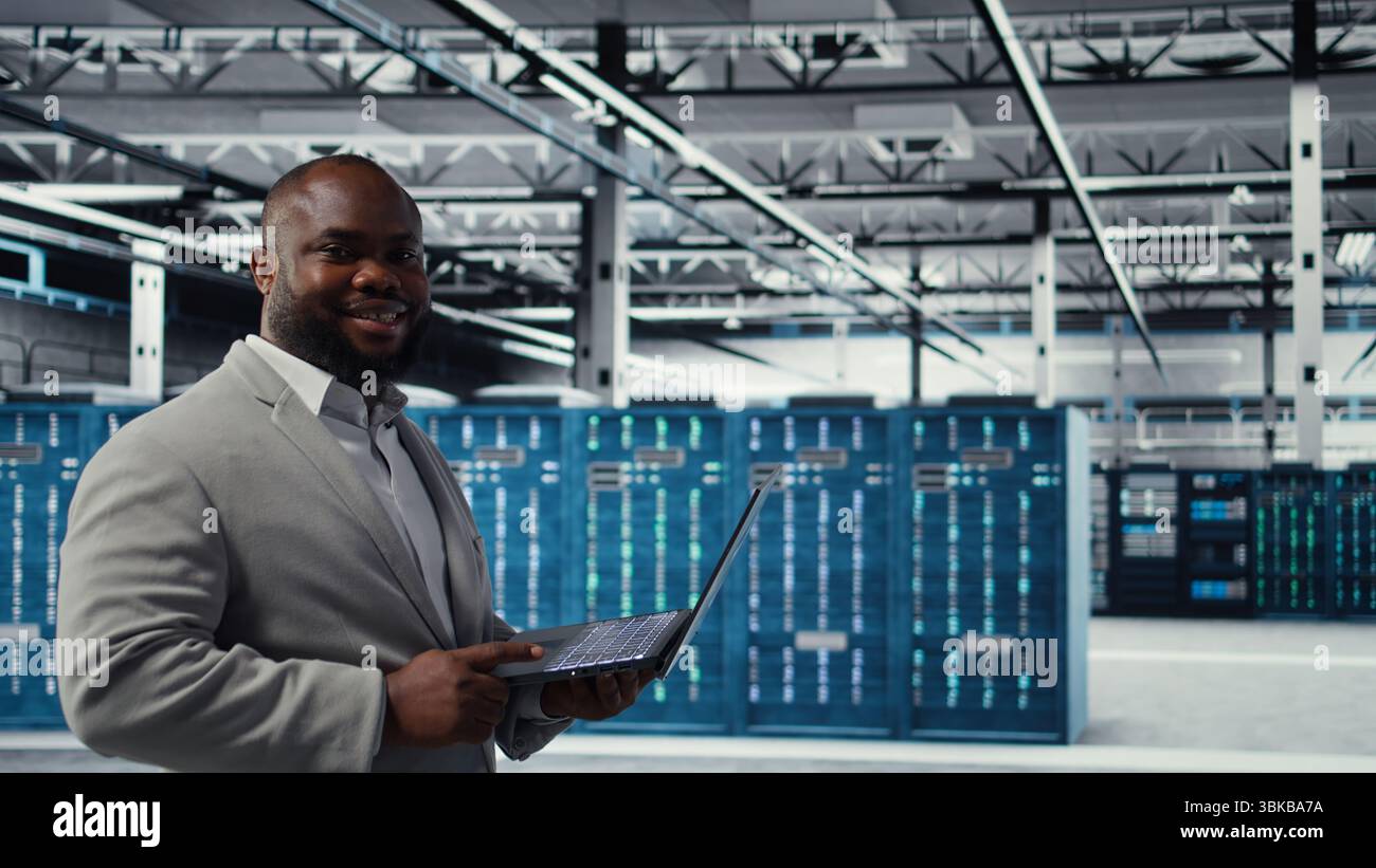 Data center software developer using tablet to do AI algorithms improvements. Programmer in server hub using laptop, maintaining databases supporting artificial intellgience applications, camera A Stock Photo