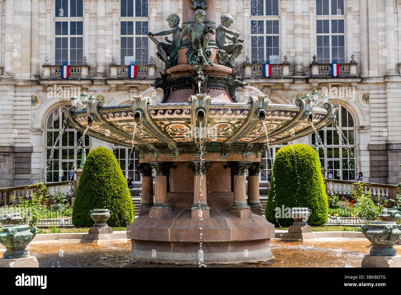 Fountain in front of Limoges Town Hall, built in 1892–1893: The fountain depicts four boys who symbolically represent the different stages of the porcelain industry: draughtsman, modeller, sculptor and decorative painter. It consists of a large basin with additional porcelain basins from the Guérin factory, a well-known porcelain manufacturer in Limoges. Place Léon Betoulle, Limoges, Nouvelle-Aquitaine, France Stock Photo