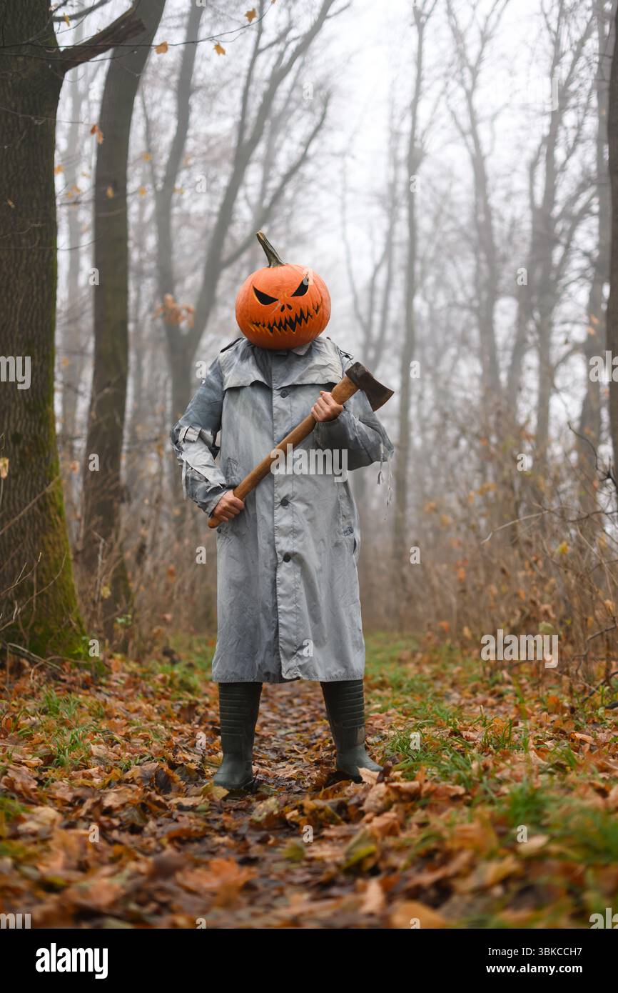 Axe-wielding scarecrow with pumpkin head stands in foggy autumn