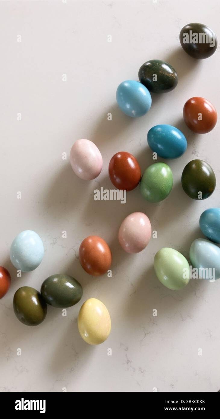 Assorted colorful eggs scattered on a light marble surface Stock Photo