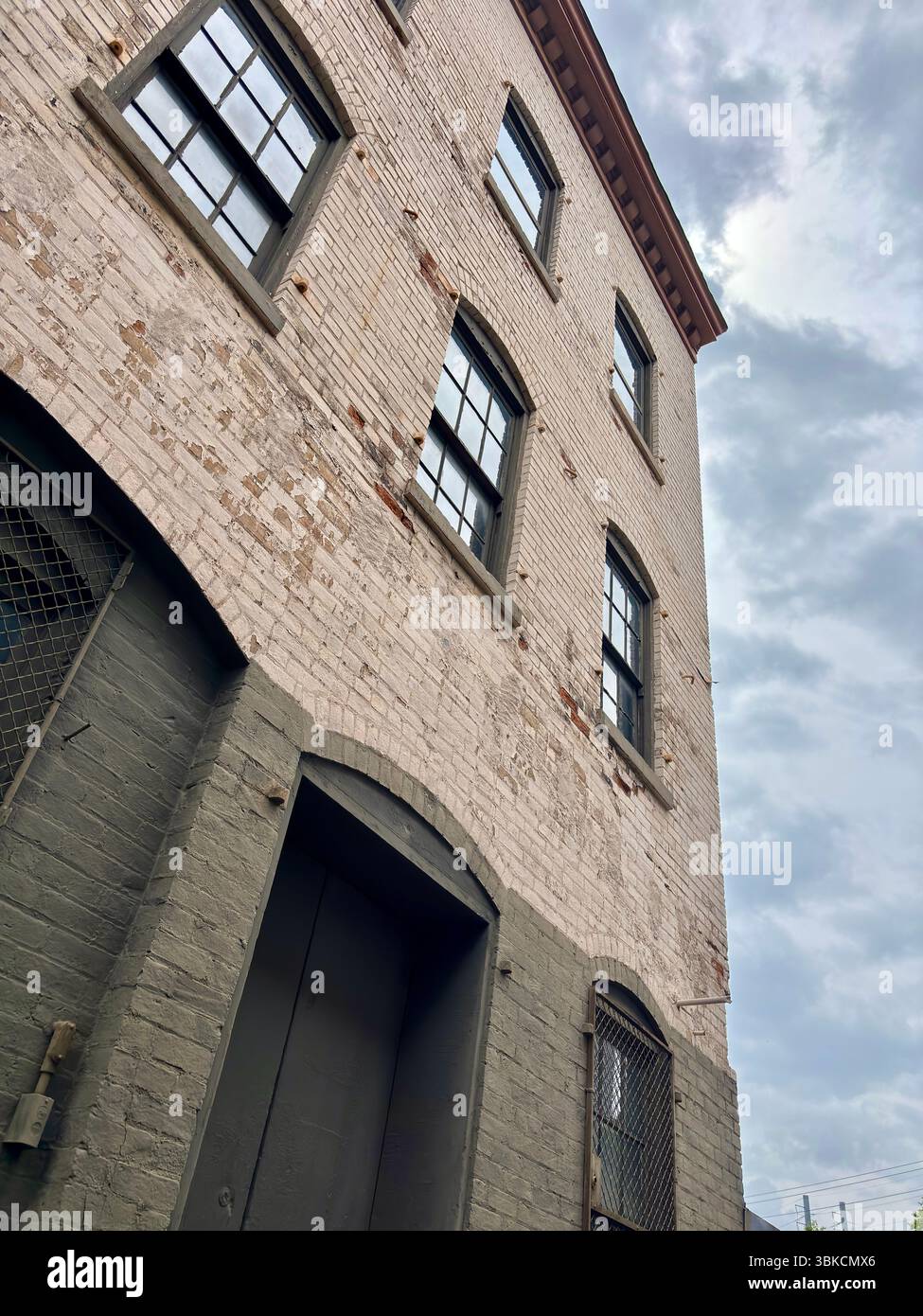 19th century brick building with arched windows under a cloudy sky ...