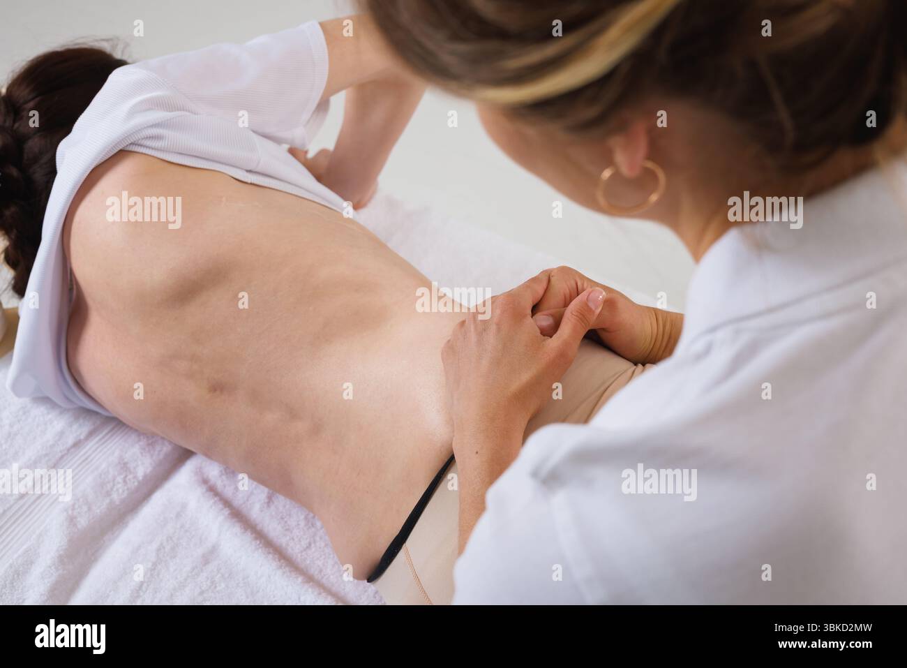 Specialist evaluates spinal deformity in patient with scoliosis or displacement for treatment, diagnostics, and rehabilitation planning. Stock Photo