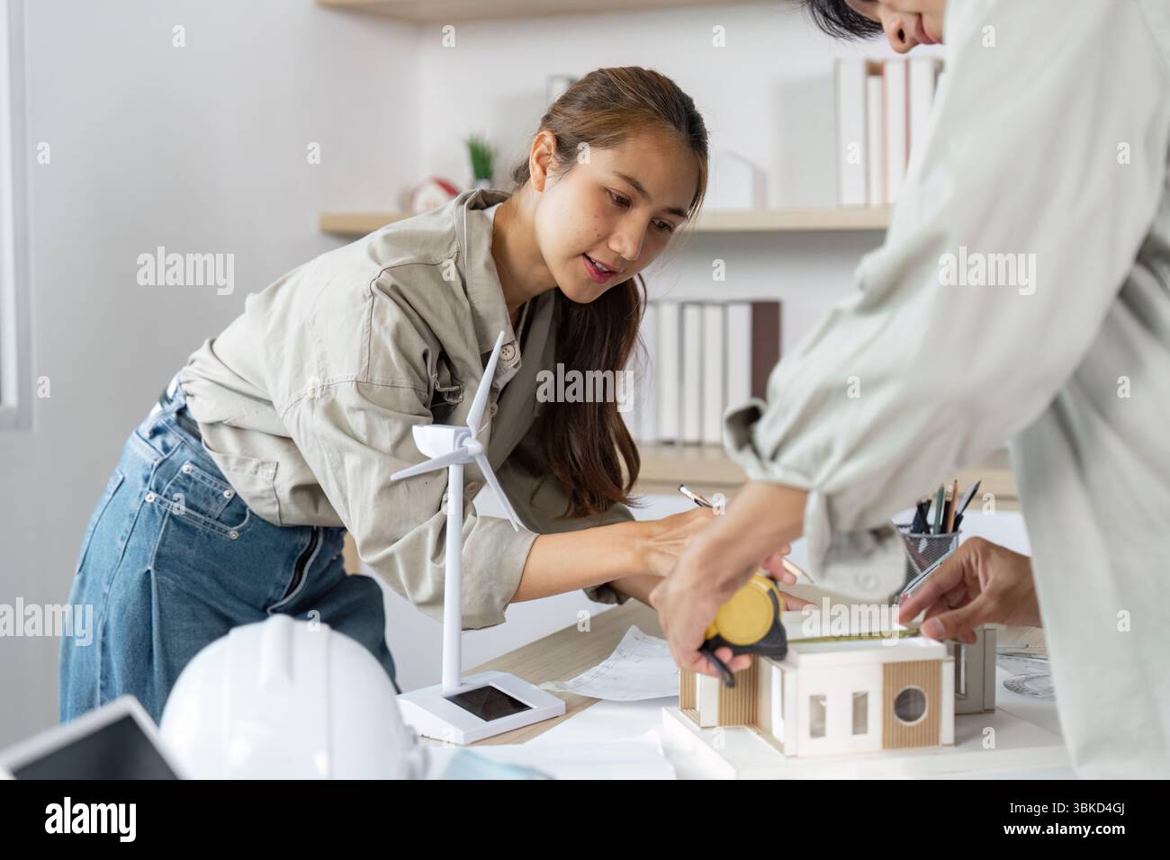 Hands-on Architectural Development. Female architect measuring a model structure. Stock Photo