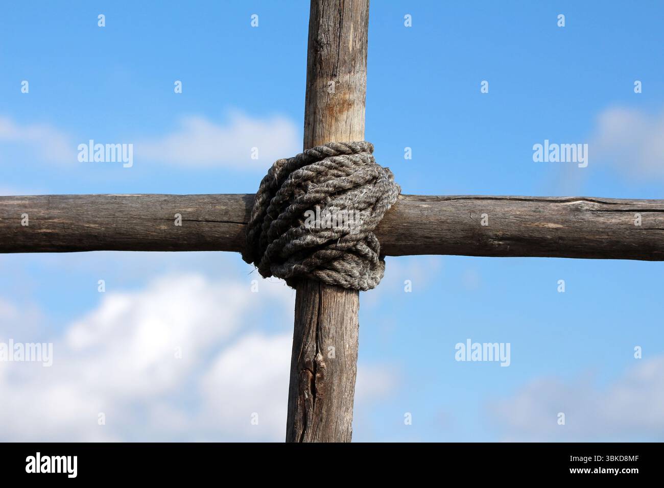 Thick rope tightly binds two weathered wooden beams at a right angle ...