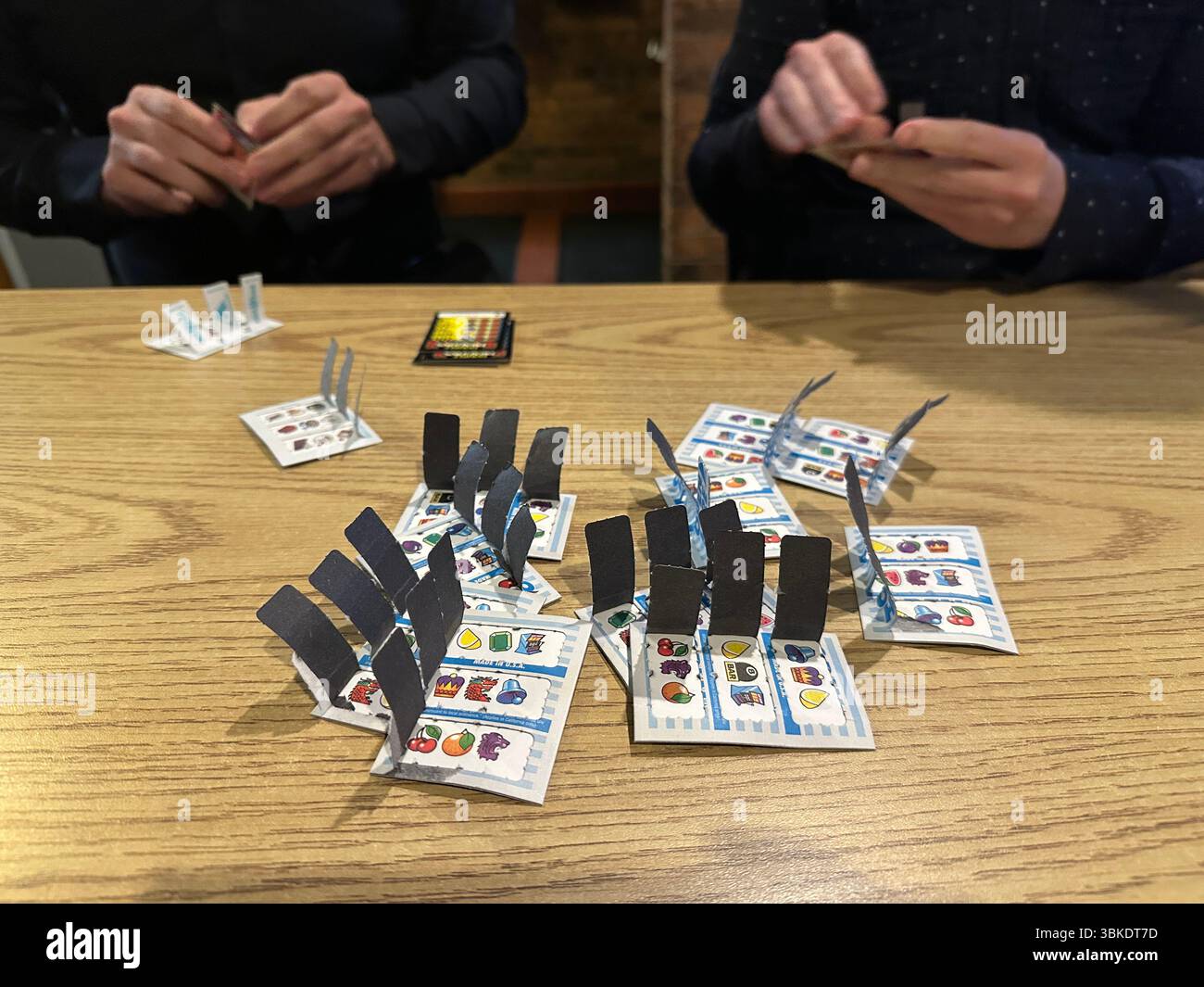 Close up of the hands of two people pulling pull tab gambling tickets in a bar in Minnesota. Stock Photo