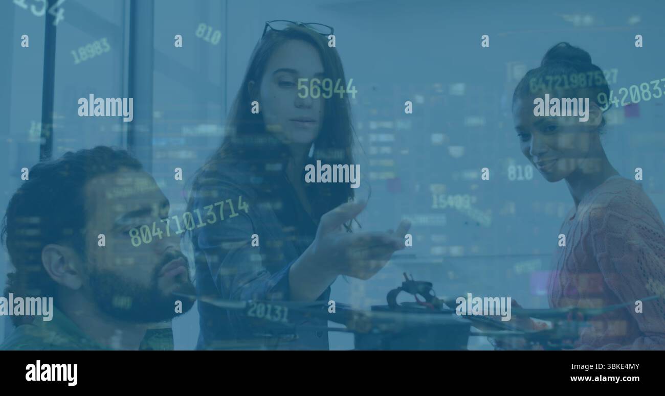 Collaborating 3 engineers analyzing quadcopter drone at office workspace with data overlay Stock Photo