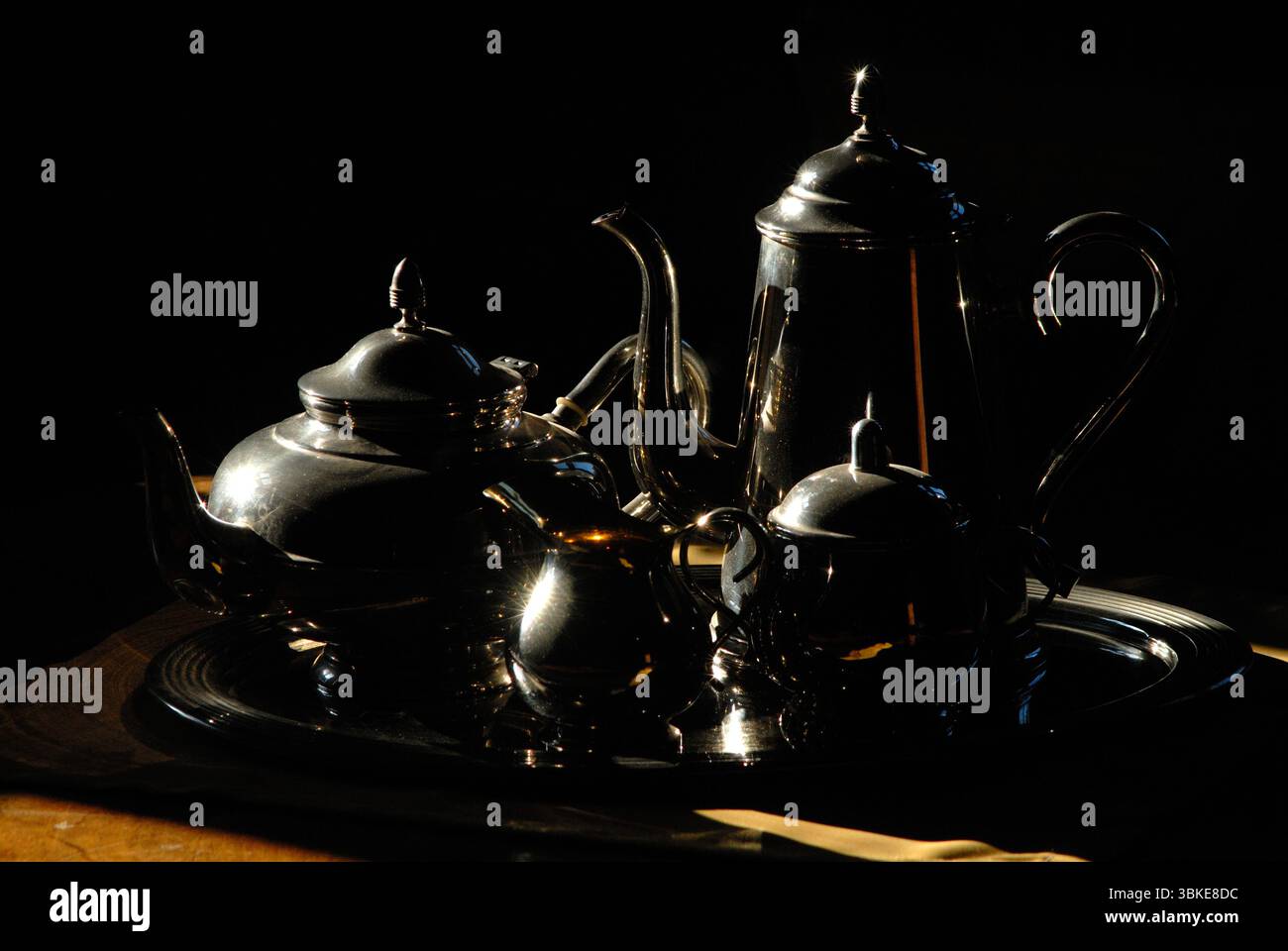 Elegant still life of an antique silver tea set, dramatically lit in the chiaroscuro (light-dark) style Stock Photo
