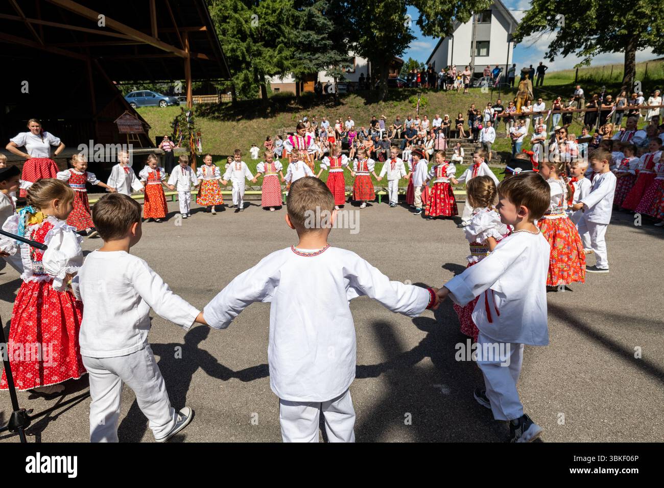 Large group of girls and boys holding hands in circle dancing traditional Sliac folk dance at Juniales festival Stock Photo