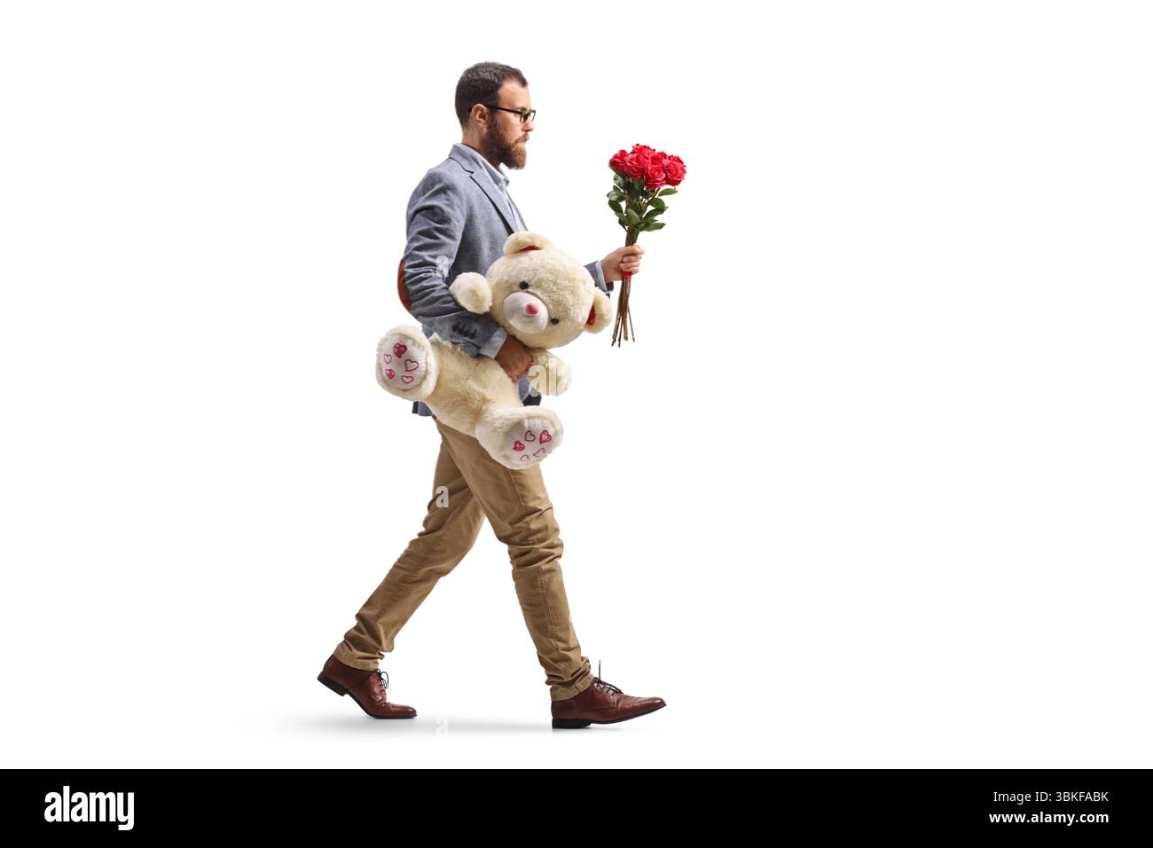 Bearded man walking with a bunch of red roses and a teddy bear isolated on white background Stock Photo